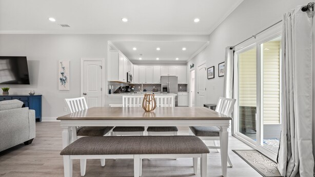 A modern kitchen with white cabinets, a wooden dining table, and a bench. - Castaway Cay - Beautiful 4 BR House with Pool (North Myrtle Beach)