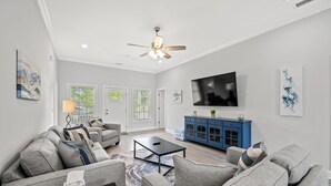 A modern living room with a grey sofa set, a coffee table, a blue cabinet, and a flat-screen TV. - Castaway Cay - Beautiful 4 BR House with Pool (North Myrtle Beach)