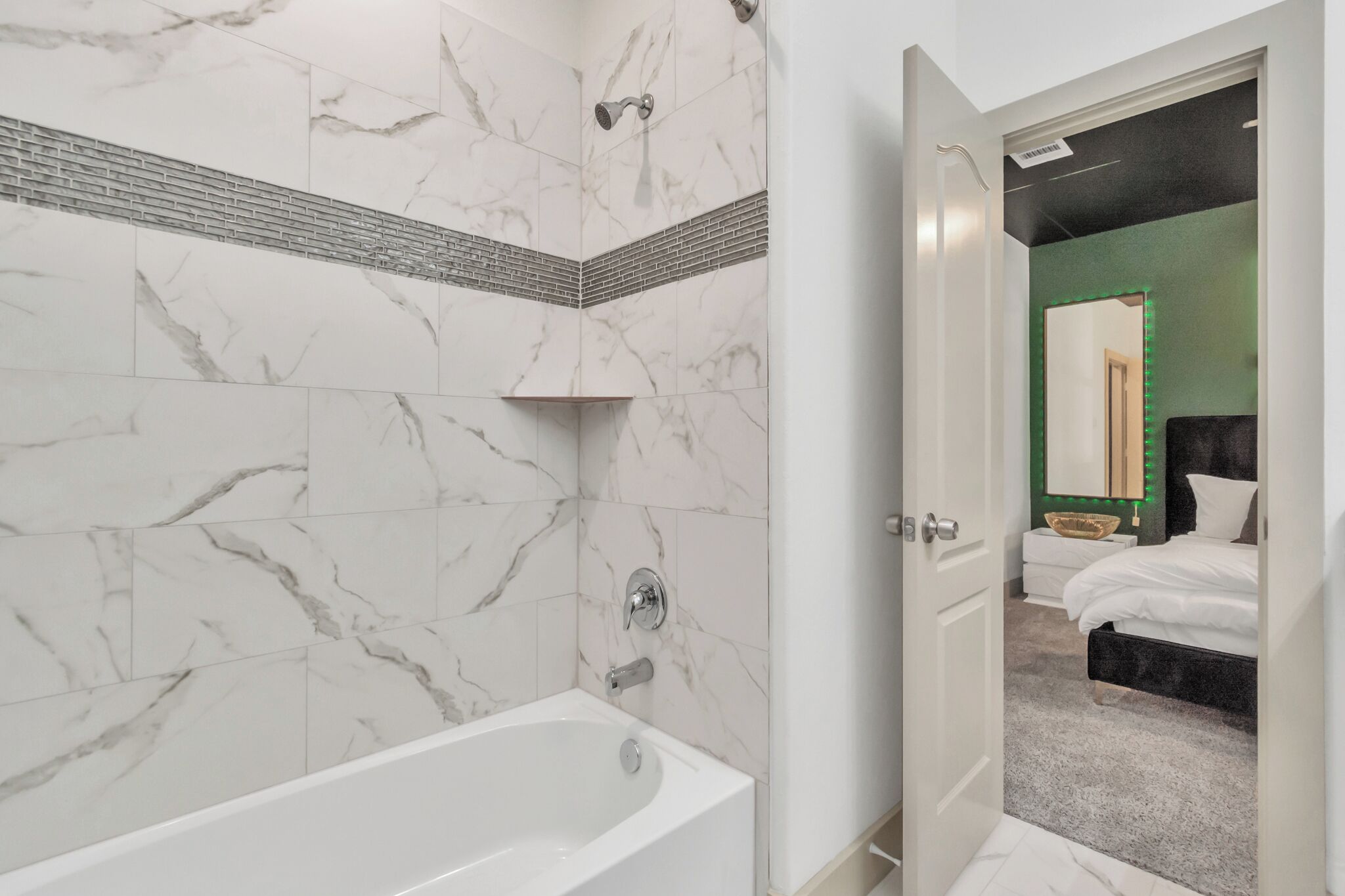 Un baño moderno con pared de mármol, una bañera y una ducha.