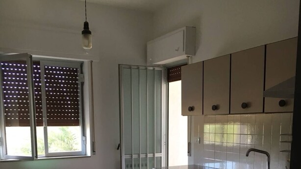 Una cocina compacta con comedor, una ventana con persianas y una puerta que da al exterior.