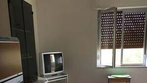 Cocina compacta equipada con refrigerador, microondas, pileta y una mesa de comedor con sillas, además de un ventanal con persianas.
