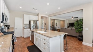 A modern kitchen with white cabinetry, a granite countertop, and a built-in oven. - Desert Golf Getaway by GPM -Tennis+Pickleball+Priv. Pool+More! Walk to Festivals (Indio)