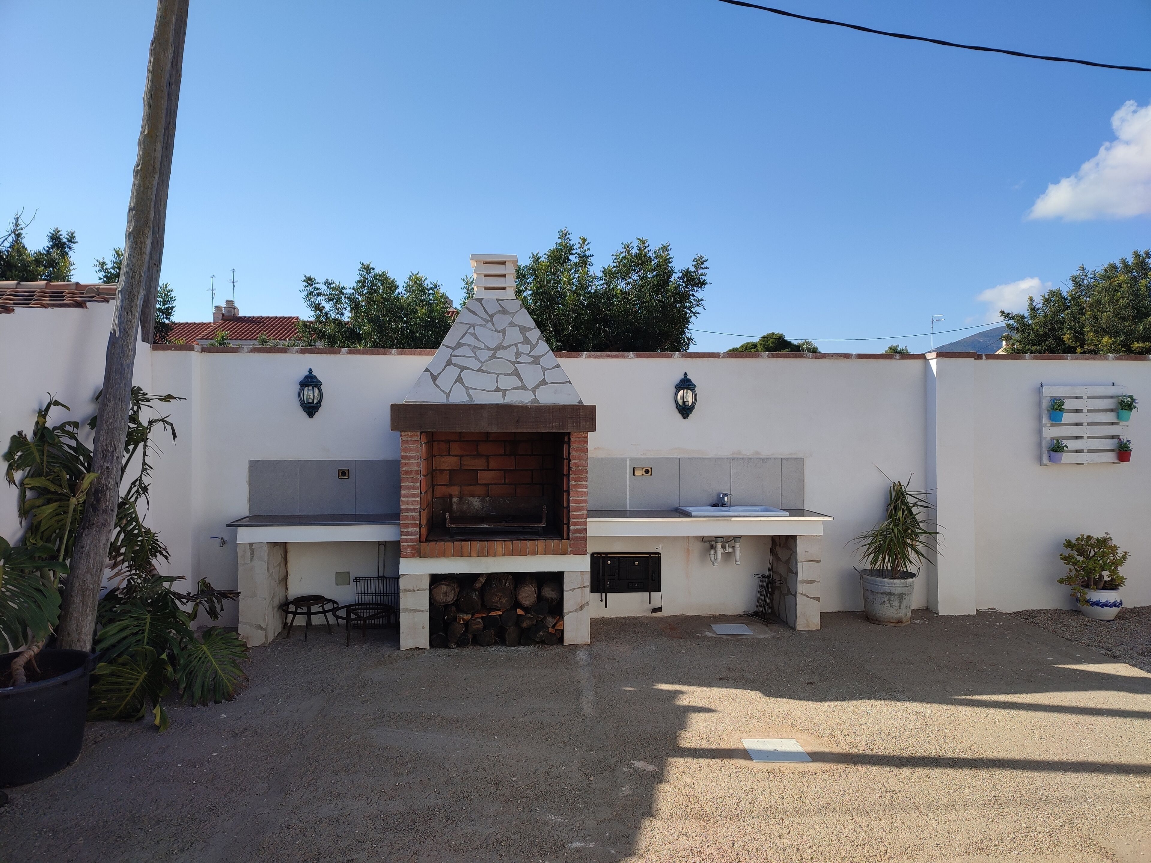 An outdoor kitchen area with a stone oven, a sink, and a small seating area.