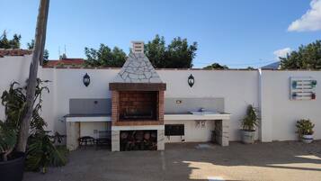 An outdoor kitchen area with a stone oven, a sink, and a small seating area.