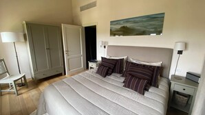 A bedroom with a bed, bedside tables, a chair, a wardrobe, and a painting on the wall. - The Valley 3 (Castelfalfi)