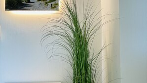 A corner of a room with a white console table, a woven plant pot, and a framed picture on the wall. - Düne 77Modern vacation apartment in Westdorf in top location (Baltrum)