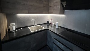 A modern kitchen with dark wood cabinets, a stainless steel sink, and a black countertop. - BIENNIAL PENTHOUSE WITH BEAUTIFUL PANORAMIC TERRACE OVER THE LAGOON FREE WI-FI (Venezia)