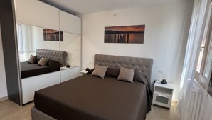 A modern bedroom with a large bed, a wardrobe, a bedside table, and a painting on the wall. - BIENNIAL PENTHOUSE WITH BEAUTIFUL PANORAMIC TERRACE OVER THE LAGOON FREE WI-FI (Venezia)