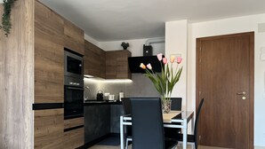 A modern kitchen with wooden cabinets, a black countertop, and a dining area with a table and chairs. - BIENNIAL PENTHOUSE WITH BEAUTIFUL PANORAMIC TERRACE OVER THE LAGOON FREE WI-FI (Venezia)