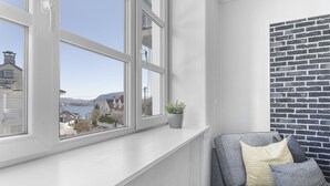 A room with a view of a body of water, a brick wall, and a grey sofa with cushions. - 3 bedroom private vacation home in vestland (Vestland)