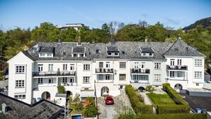 A large, white, multi-story building with a symmetrical facade, multiple balconies, and a central courtyard with a car parked in front. - 3 bedroom private vacation home in vestland (Vestland)
