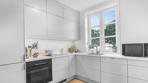 A modern kitchen with white cabinetry, a built-in oven, a microwave, and a window providing natural light. - 3 bedroom private vacation home in vestland (Vestland)