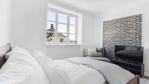 A bedroom with a large window, a brick wall, and a flat-screen TV. - 3 bedroom private vacation home in vestland (Vestland)