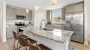 A modern kitchen with granite countertops, stainless steel appliances, and pendant lighting. - Beach Vibes in Navarre (Navarre)
