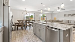 A modern kitchen with a central island, stainless steel appliances, and pendant lighting. - Beach Vibes in Navarre (Navarre)
