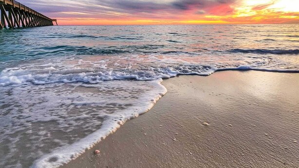 A beach with a pier extending into the ocean at sunset. - Beach Vibes in Navarre (Navarre)