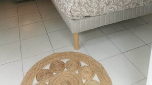 Een slaapkamer met een bed, twee bedlampen, een klein nachtkastje en een geweven vloermat.