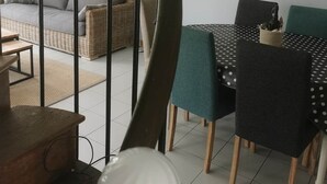 Een eethoek met een tafel en stoelen, een trap met een metalen leuning, en een aan de muur bevestigde fiets.