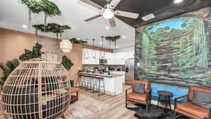 Une cuisine moderne avec des meubles blancs, un îlot central et des plantes suspendues.