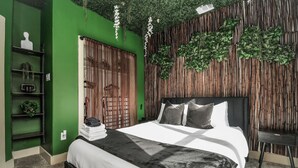 Une chambre moderne avec un mur d’accent vert, un grand lit avec une literie blanche, une tête de lit en bois et un mur vertical en bambou.