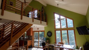 Une cuisine spacieuse avec un coin repas, un escalier et de grandes fenêtres.