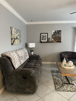 Relax in this stylish living room with a dark grey sofa, patterned throw blanket, and a wooden coffee table.