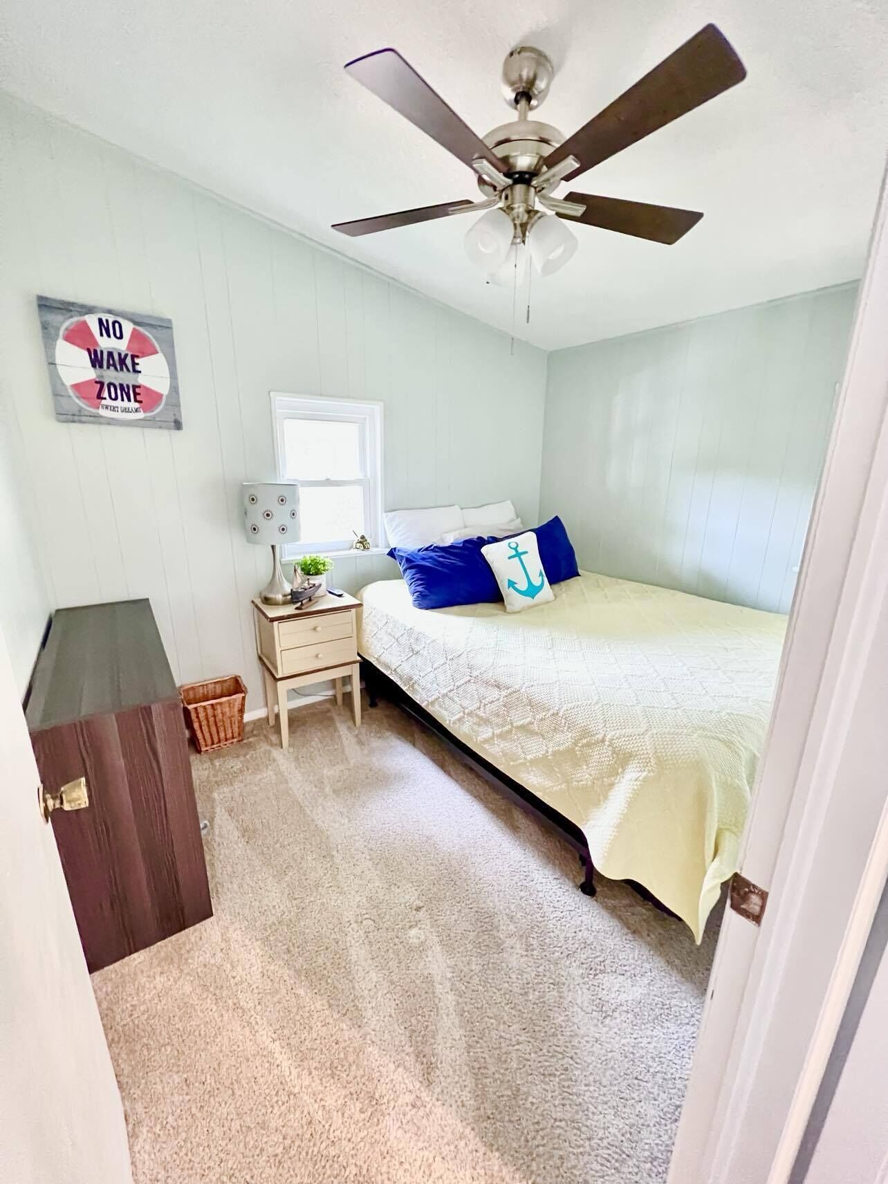 Une chambre à coucher avec un lit, une table de chevet, une lampe et un ventilateur de plafond.