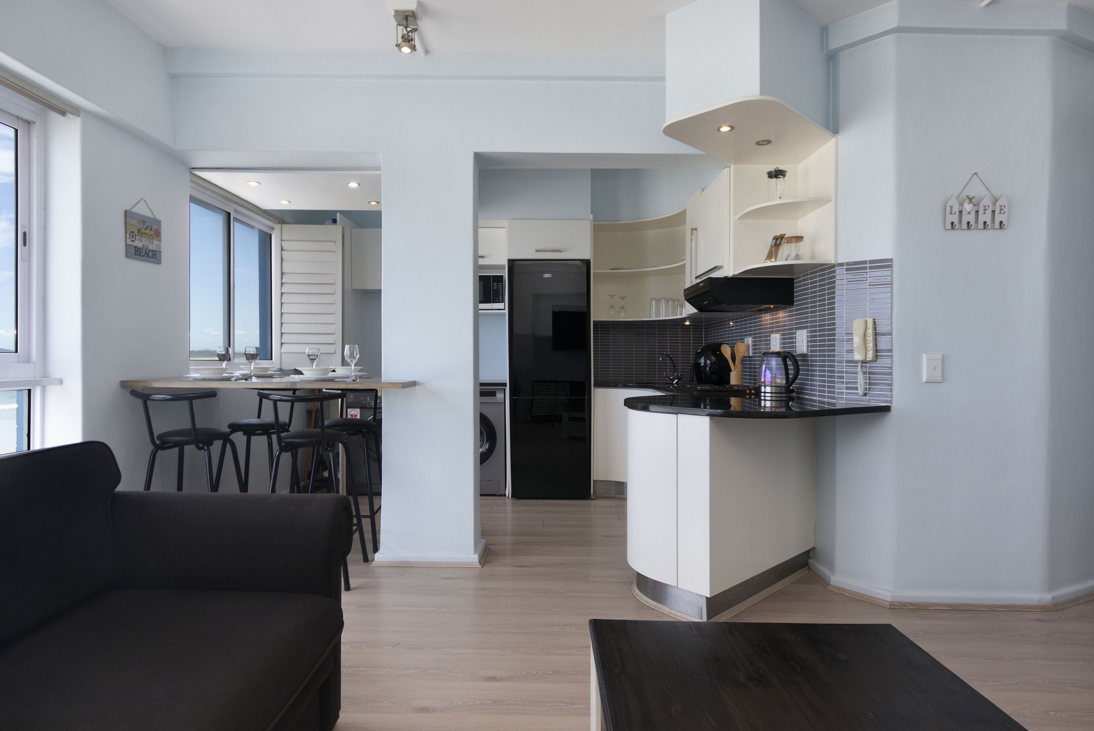 A modern kitchen with a central island, a dining area with a sofa and chairs, and a view of the living room.