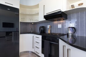 A modern kitchen with white cabinetry, a black stove, and a tiled backsplash.