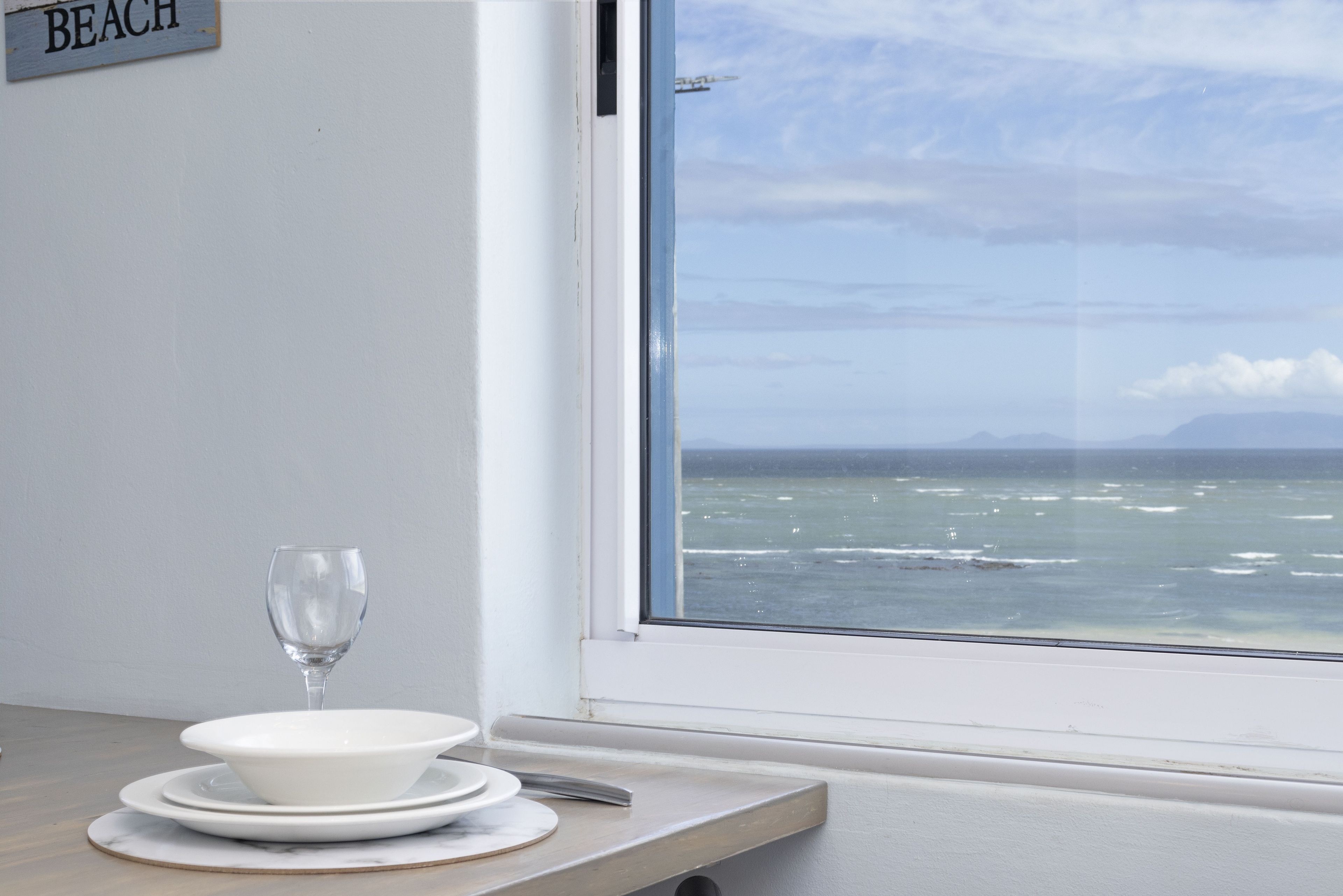 A table with a glass, plates, and a knife. A sign on the wall reads "BEACH".