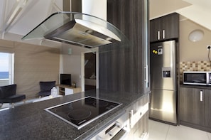 A modern kitchen with a built-in stove, stainless steel appliances, and dark cabinetry. - Dolphin Beach H301 (Cape Town)