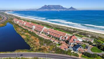 An aerial view of a coastal hotel with multiple buildings, a road, and a beach.