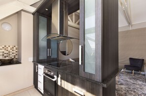 Une cuisine moderne avec des meubles de rangement aux couleurs sombres, une plaque de cuisson en verre et un four encastré.