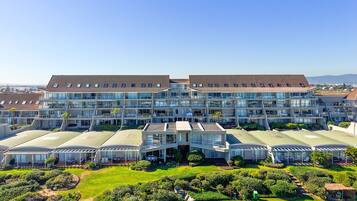 A modern hotel with multiple floors, large glass windows, and a well-maintained garden.