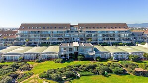 Un hotel moderno con varios pisos, amplias ventanas de vidrio y un jardín bien cuidado.