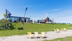 Eine Strandlage mit Gebäude, Flaggen und Liegestühlen.