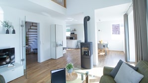 Ein geräumiger Wohnbereich mit einem modernen Kamin, einem Essbereich und einer Küche im Hintergrund.