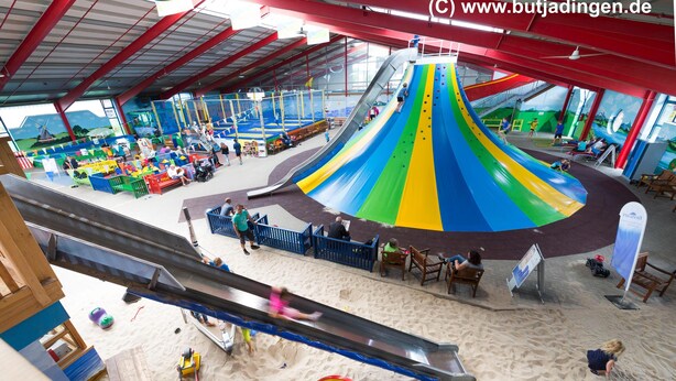 Ein großer Indoor-Freizeitpark mit einer bunten Rutsche und verschiedenen Spielbereichen.