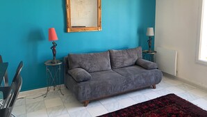 Quarto com paredes verde-água, sofá, duas luminárias, espelho e janela.