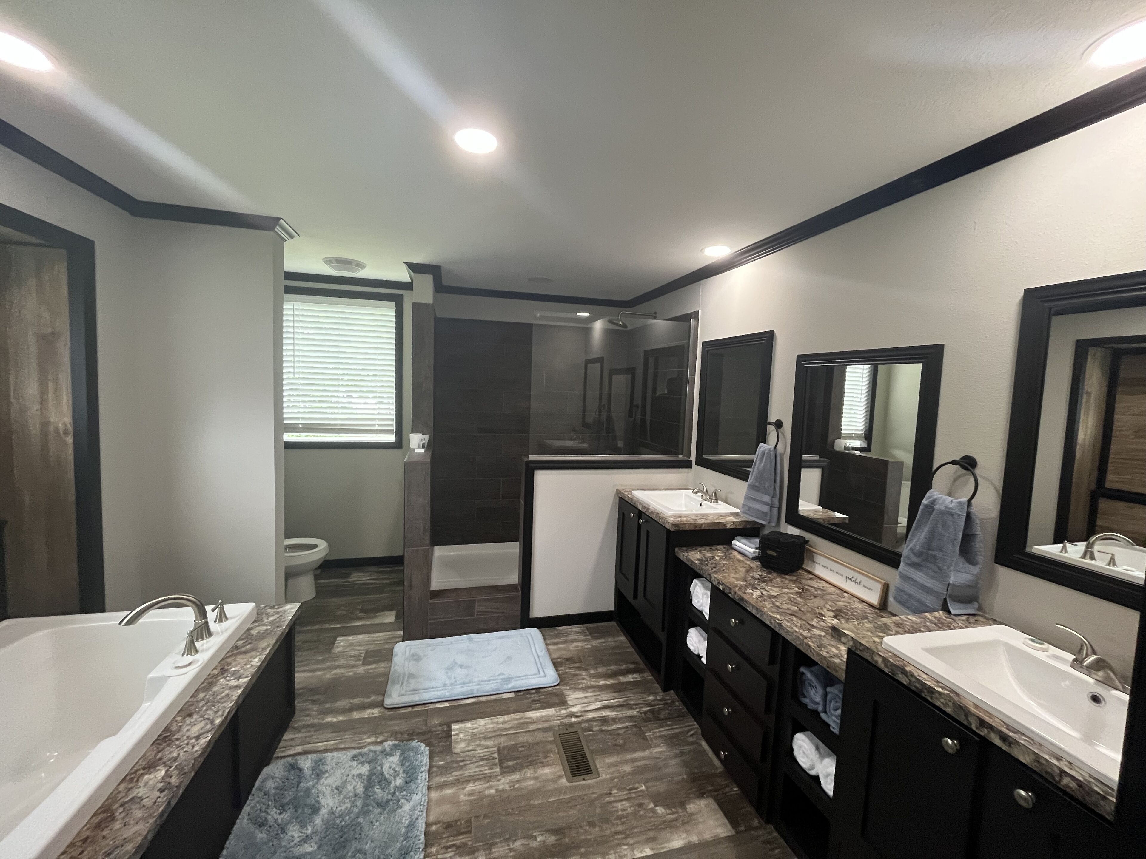 A modern bathroom with a large bathtub, two sinks, and a walk-in shower.