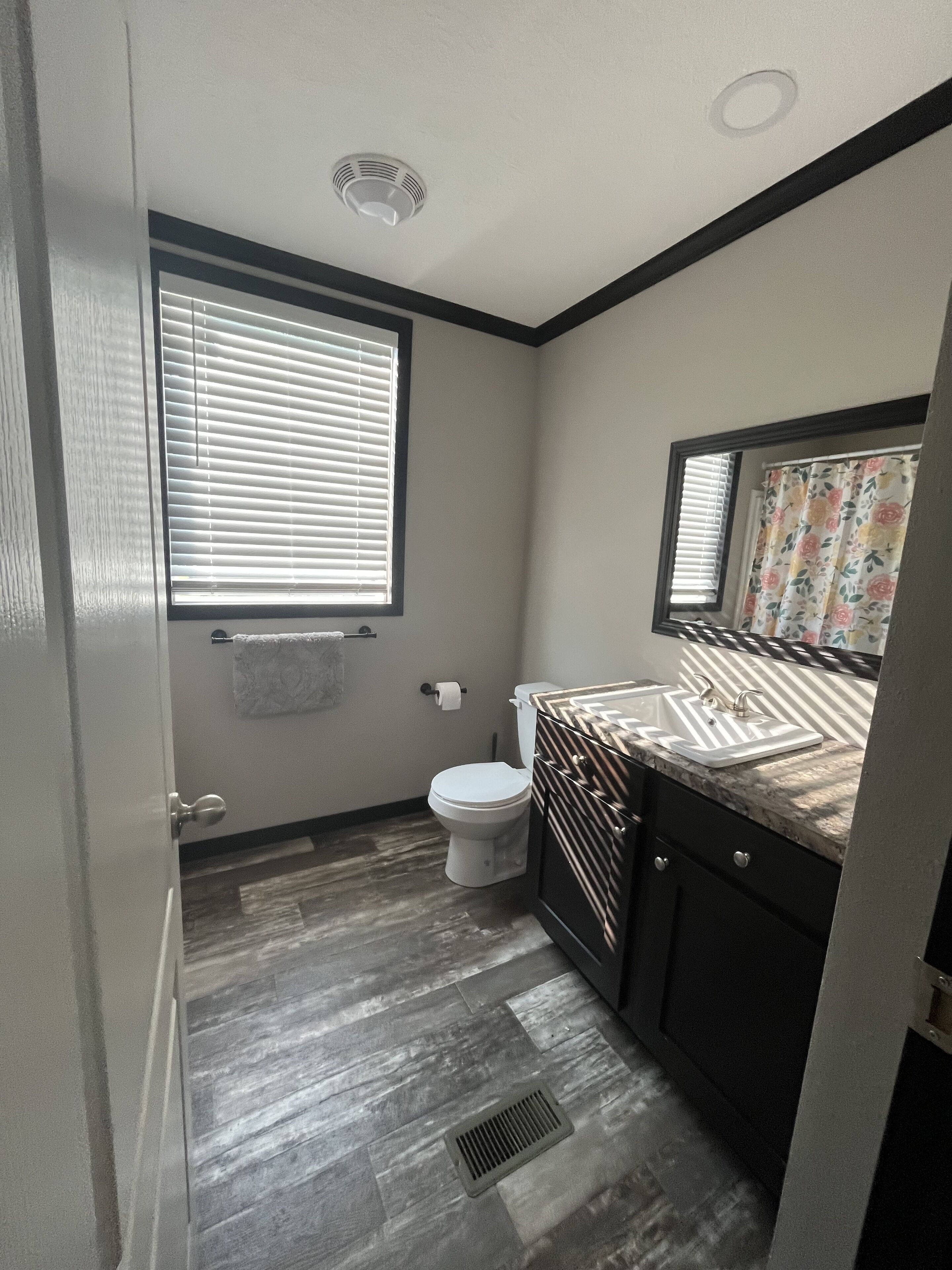 A small bathroom with a toilet, sink, and window.