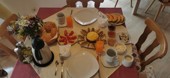 Una mesa de desayuno con diversas opciones de comida, como pan, fruta y un plato de huevos revueltos.