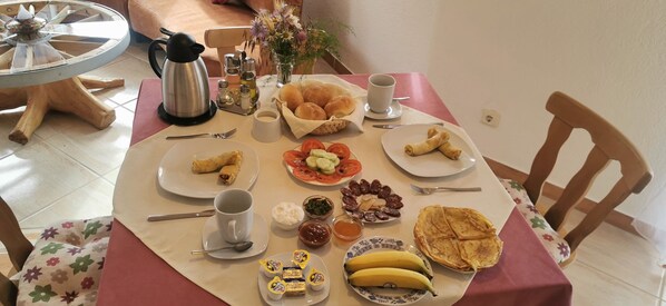 Una mesa de desayuno con diferentes alimentos, una cafetera y aderezos.