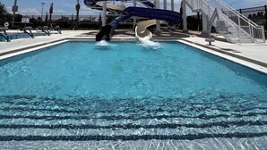 Ein Wasserpark mit Schwimmbecken, Wasserrutschen und einem überdachten Bereich.