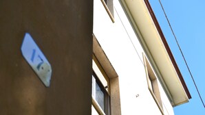 Un coin d’immeuble avec une fenêtre visible et une partie d’un mur orné d’un autocollant.