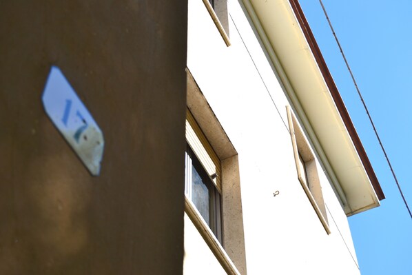 A building corner with a visible window and a part of a wall with a sticker.