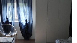 Une chambre à coucher avec un lit, une chaise, une armoire et une fenêtre avec des rideaux.