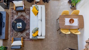 A modern living room with a sofa, a round coffee table, and a dining table with yellow chairs. - Cozy 2BR condo w/ valley views (Vernon Township)