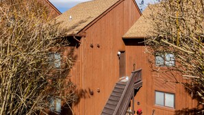 A wooden building with a staircase leading to a door, surrounded by trees. - Cozy 2BR condo w/ valley views (Vernon Township)