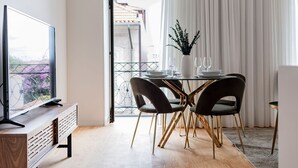 A modern dining area with a glass table, dark chairs, and a white vase with plants. - Almada 551 - 3.1 l Luxury Living by LovelyStay (Porto)